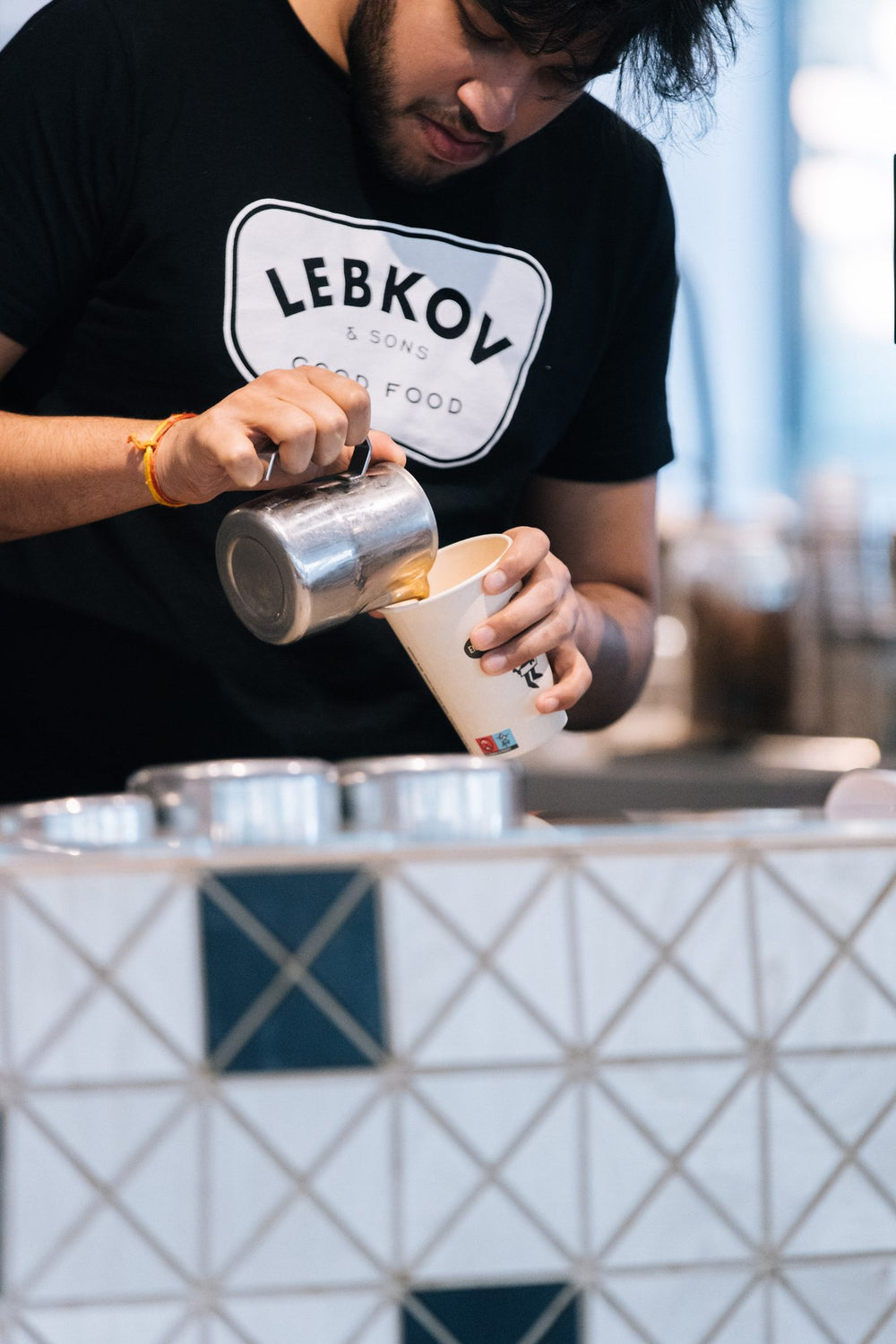 Lebkov team member pouring milk for a cappuccino