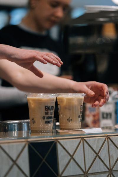 A barista handing over two iced coffees