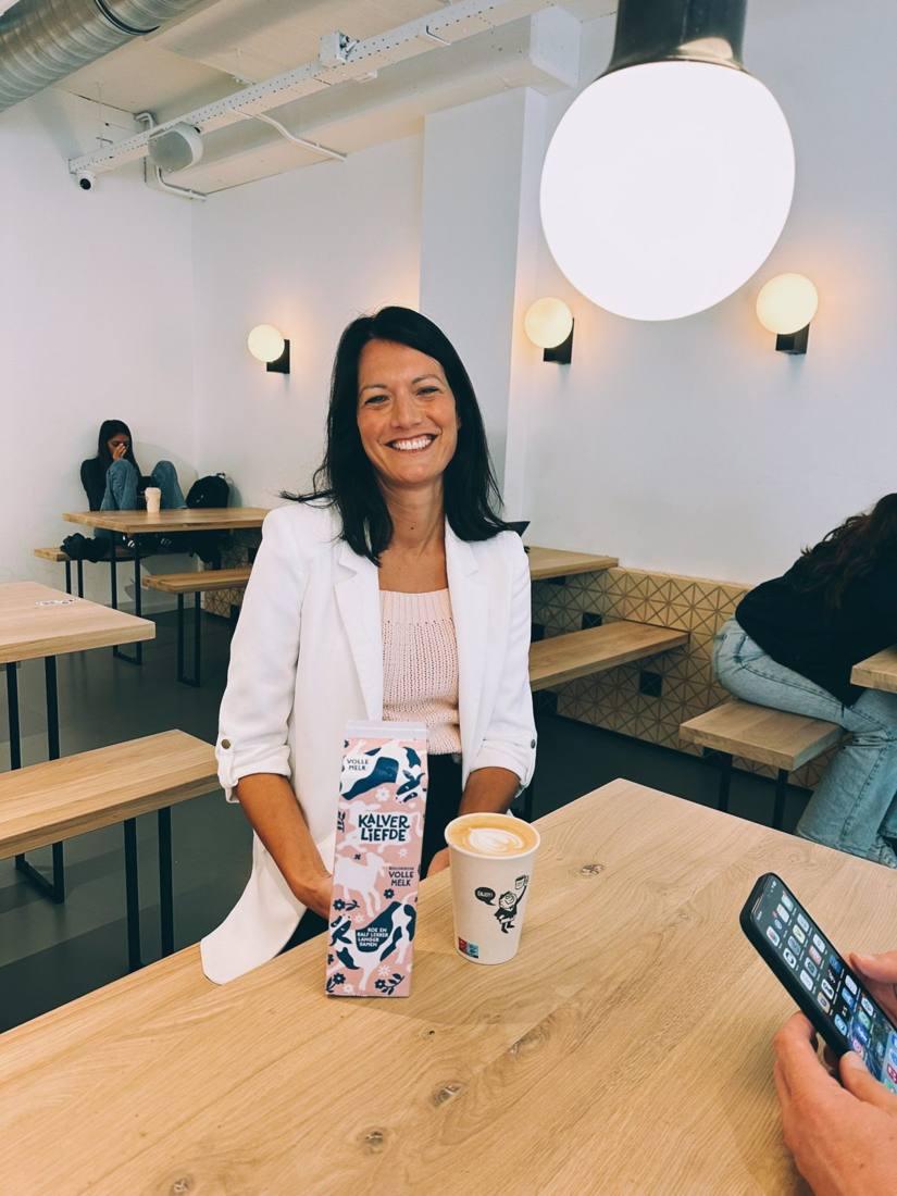 Janina, founder of Kalverliefde, with a cappuccino and a carton of Kalverliefde milk at Lebkov